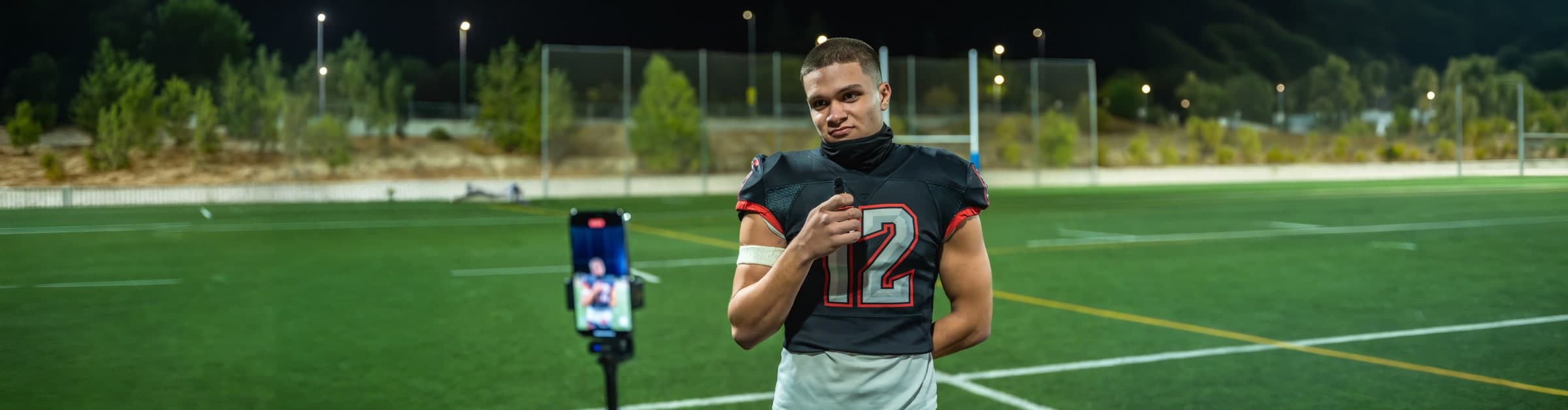 A football player is recorded on a phone on the field at night