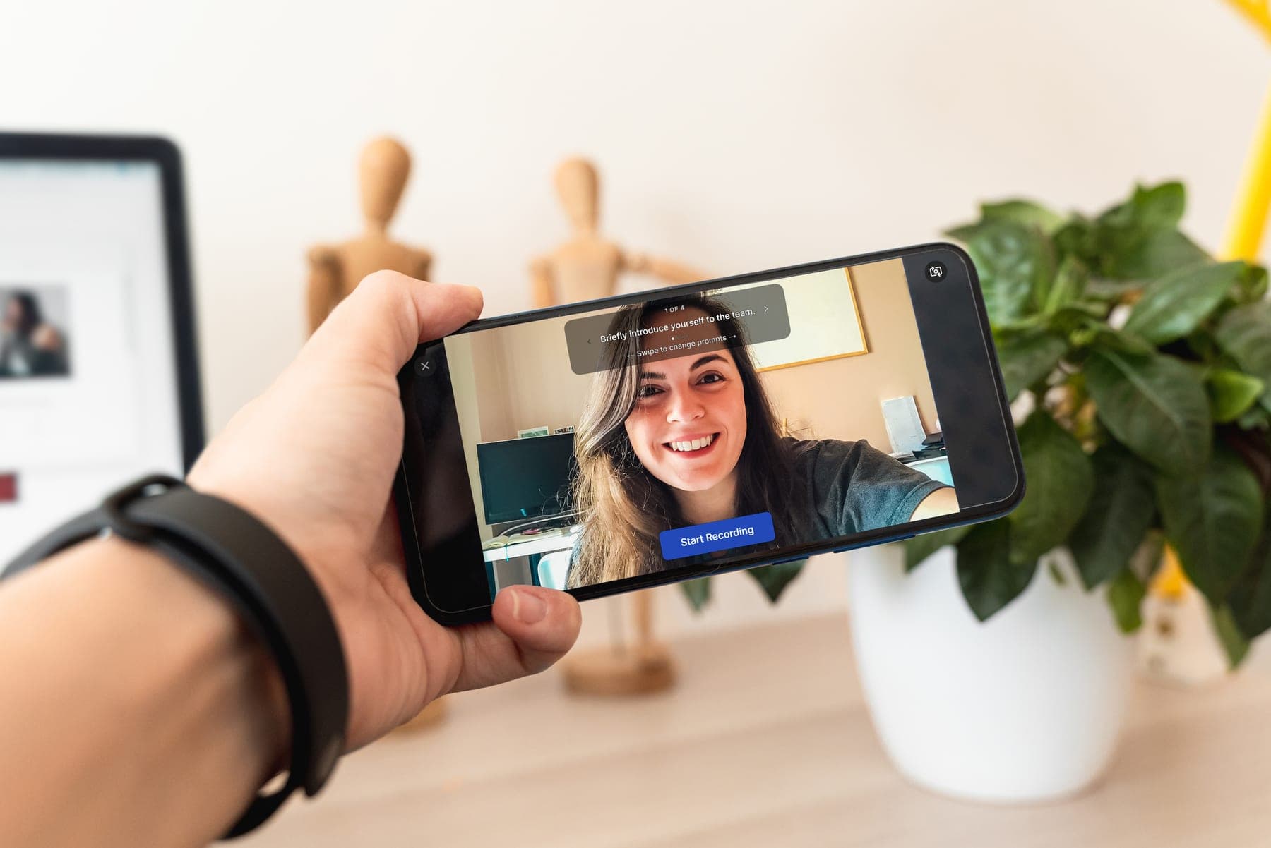 A person holds a phone while someone records a guided video response