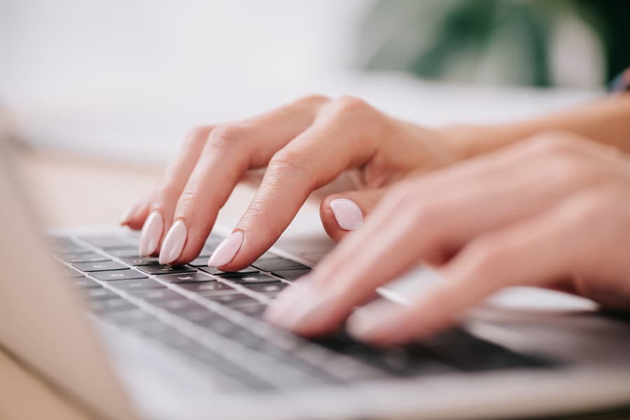 Hands typing a video request on a laptop keyboard